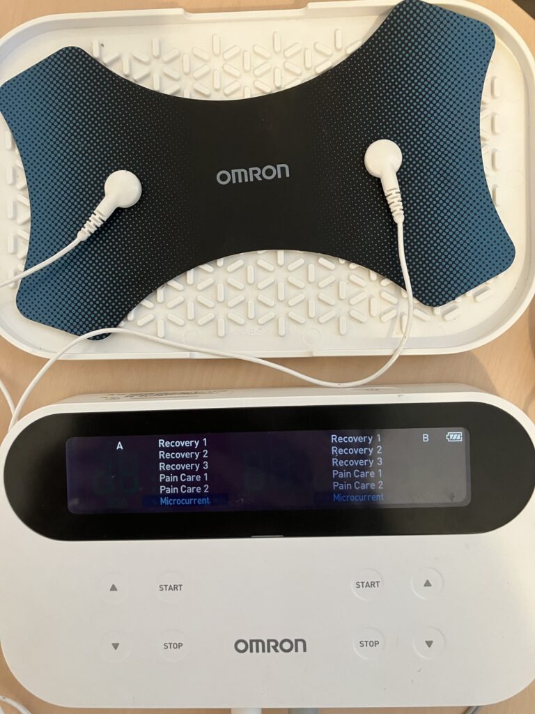 オムロン超音波治療器の本体と蝶型の大きなパッドの使用画面