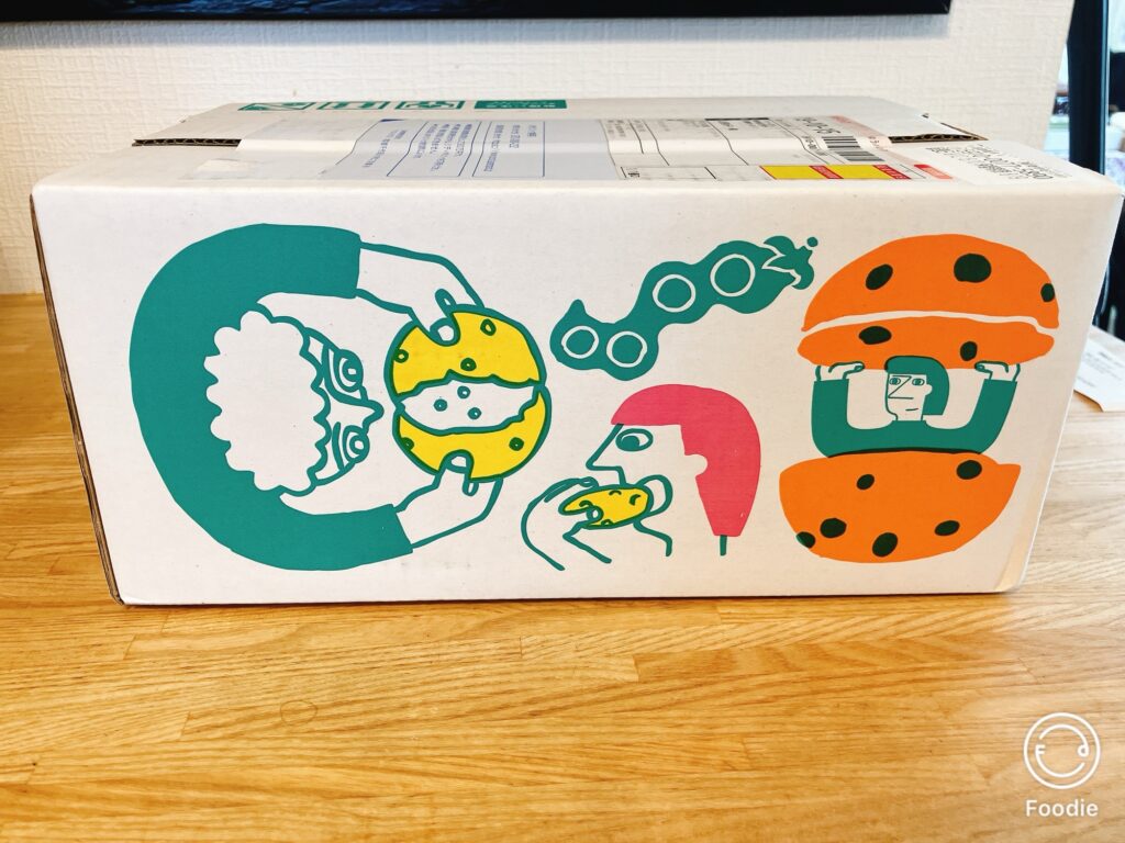 ゼンブヌードルが届いた外箱。イラスト入りの可愛らしいデザインで、枝豆やパンを持つ人物が描かれている。
