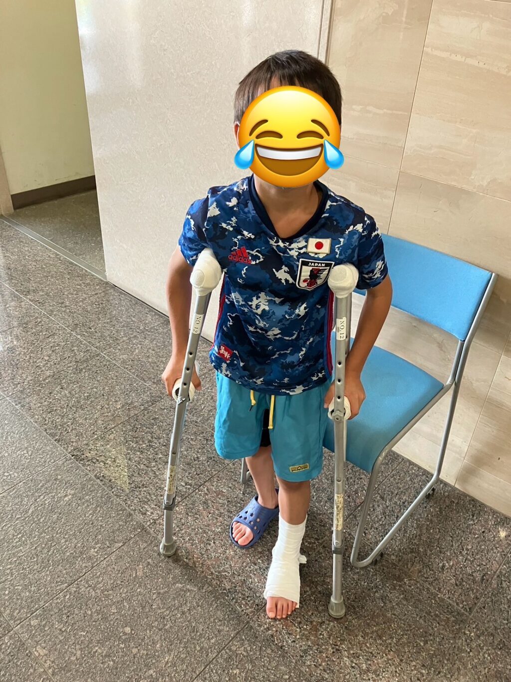病院内で松葉杖を使い、足をギプスで固定している小学生サッカー少年